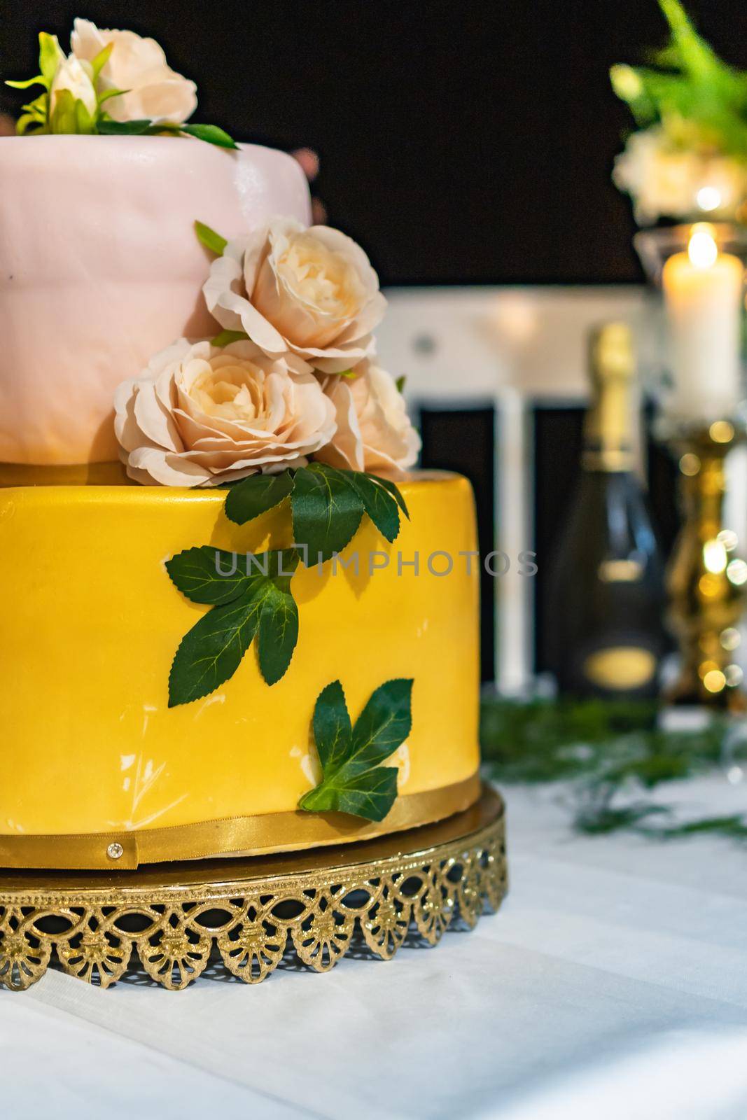 Pink and yellow wedding cake standing on table with colorful and beauty decorations around