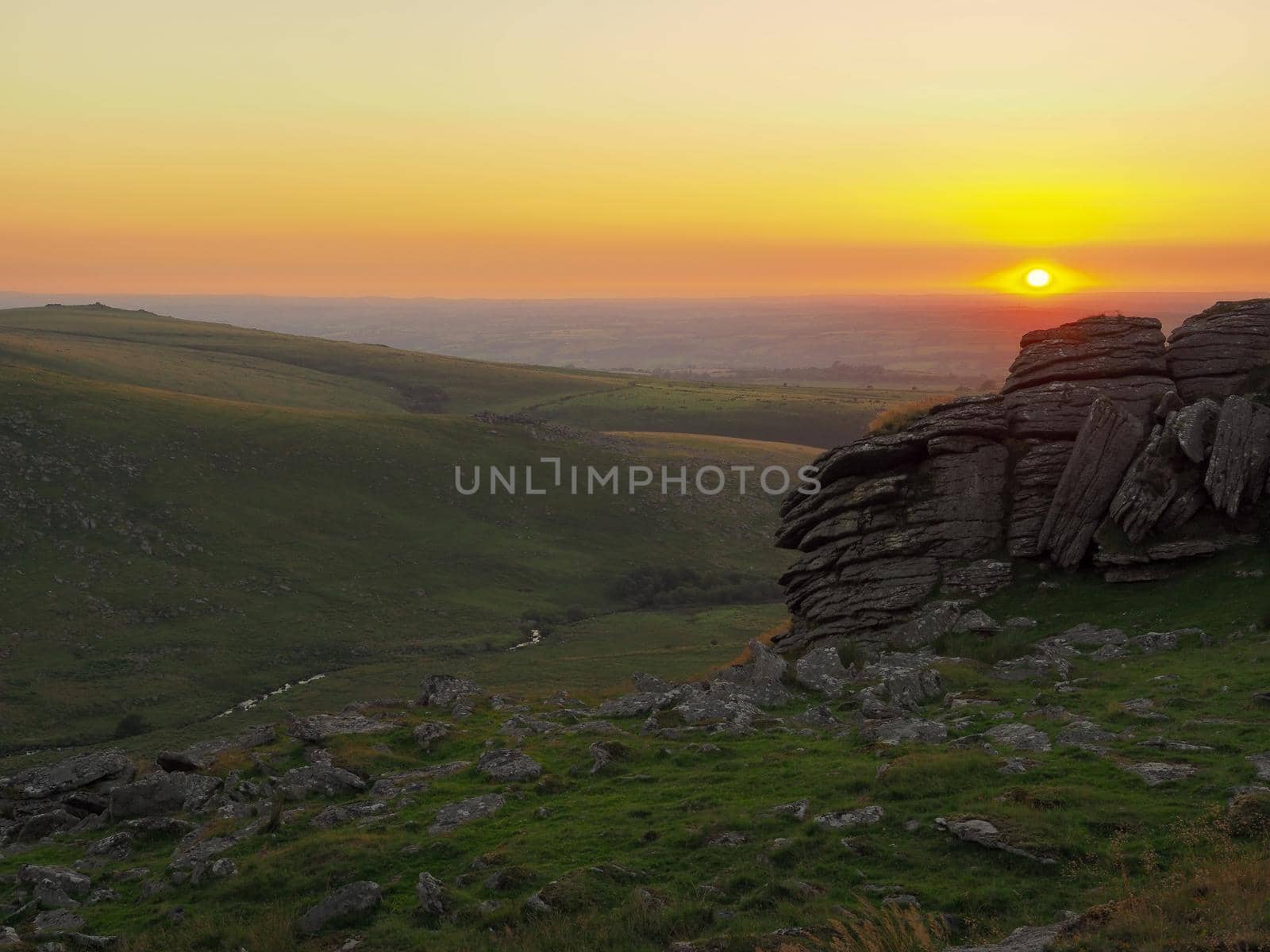 Sunset in a cloudless sky from Black Tor looking down over the West Okement Valley and across to Shelstone Tor and Sourton Tors, Dartmoor National Park, Devon, UK