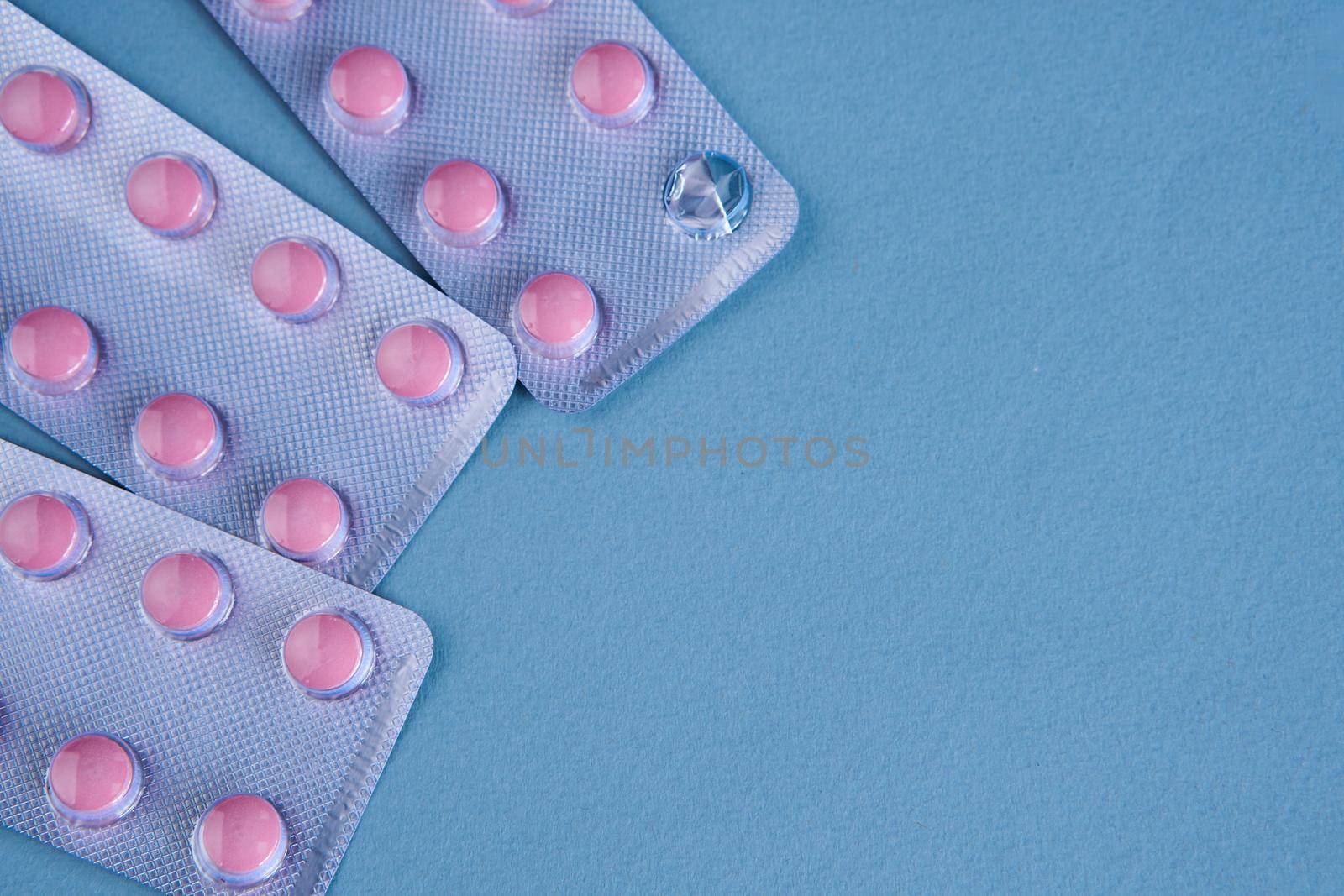 pink pills in packs vitamins pain reliever blue background. High quality photo