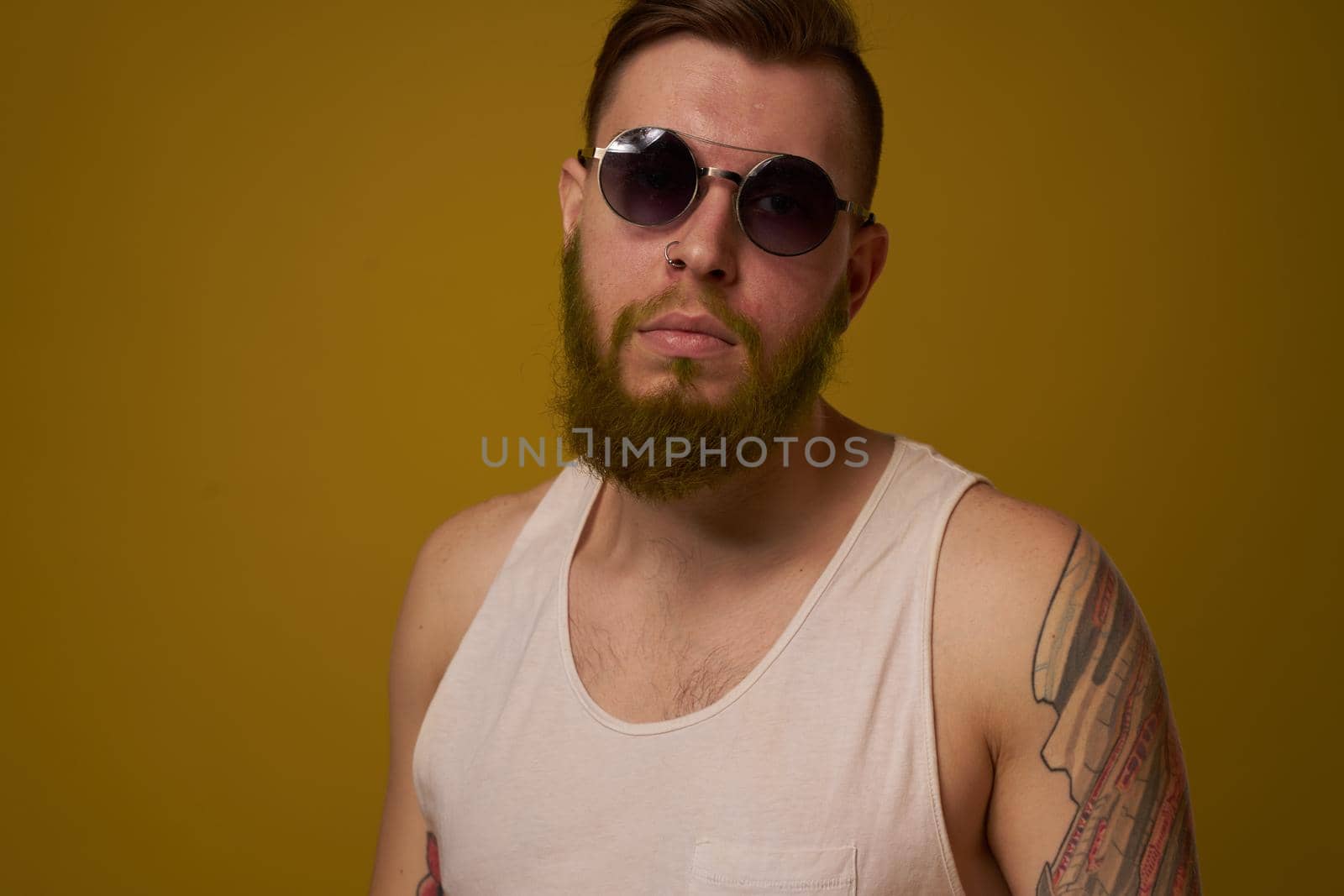 a bearded man with a serious expression in a white t-shirt with tattoos on his arms by Vichizh