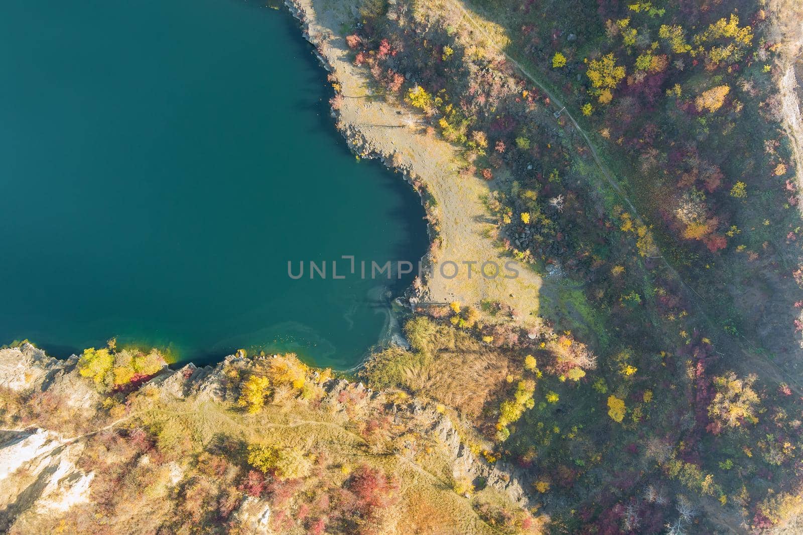 Artificial lake in a quarry with turquoise background of the clearwater autumn season by ungvar