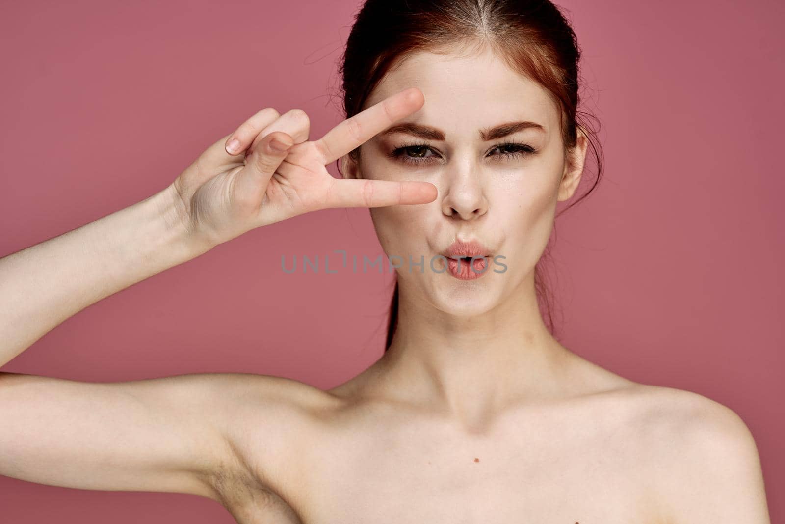 cheerful woman with bare shoulders posing clear skin pink background. High quality photo