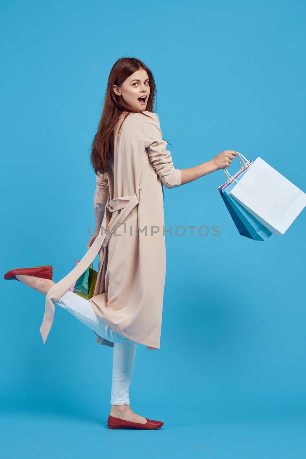 cheerful woman with multicolored bags posing blue background. High quality photo