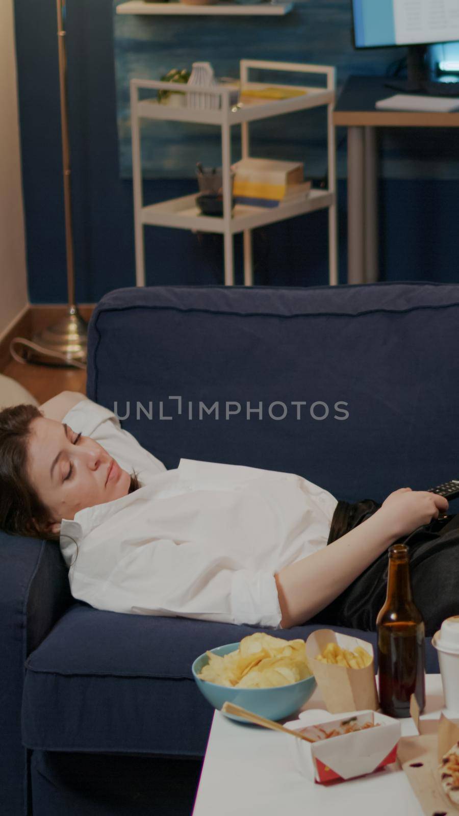 Sleepy adult relaxing on sofa after eating takeaway meal by DCStudio