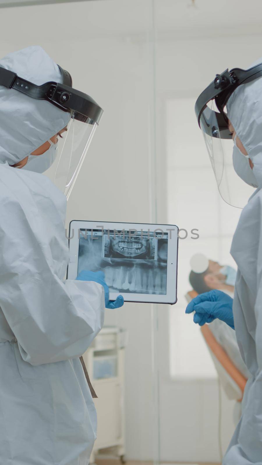 Stomatologists with ppe suits holding digital tablet with teeth x ray by DCStudio