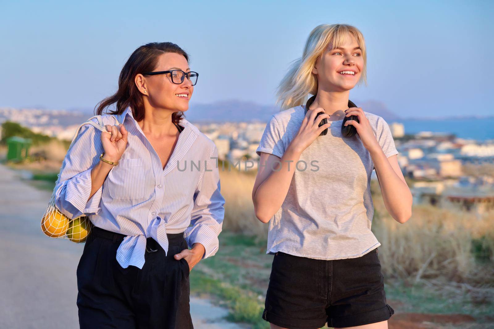 Summer walk of smiling mom and teenage daughter. Time together, family, communication parent-child adolescent, vacation, weekend, mother and daughter teenager concept