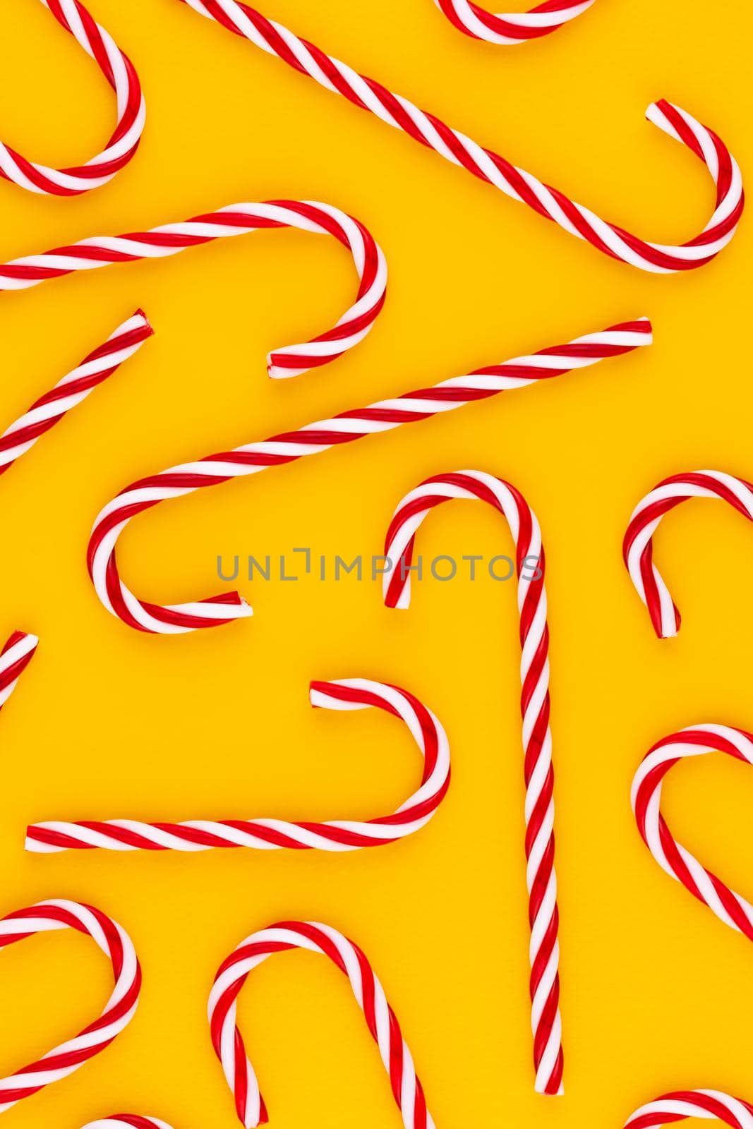 Christmas candy cane lied on yellow background. Flat lay and top view.