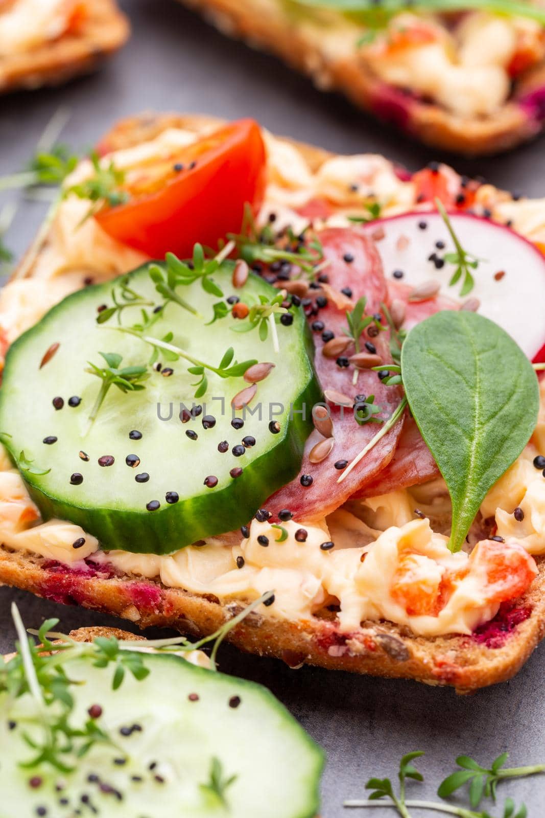 Sandwiches with cream cheese, vegetables and salami. Sandwiches with cucumber, radish, tomatoes, salami on a gray background, top view. Flat lay.