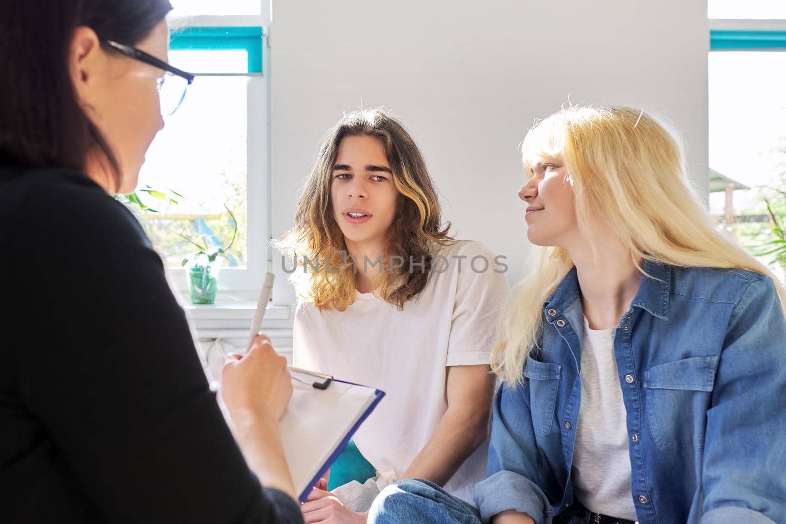 Female teacher talking to two teenage students. Guy and girl 16, 17 years old at the meeting of counselor, mentor. Adolescence, psychology, knowledge, therapy, education, high school, people concept