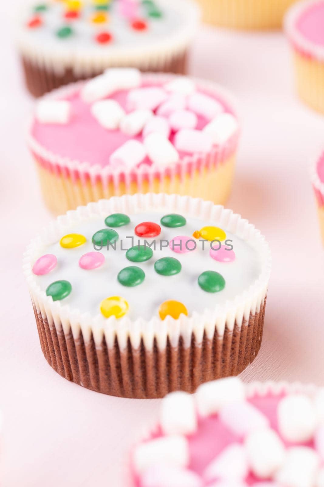 Colorful cupcakes on a pink background. by gitusik