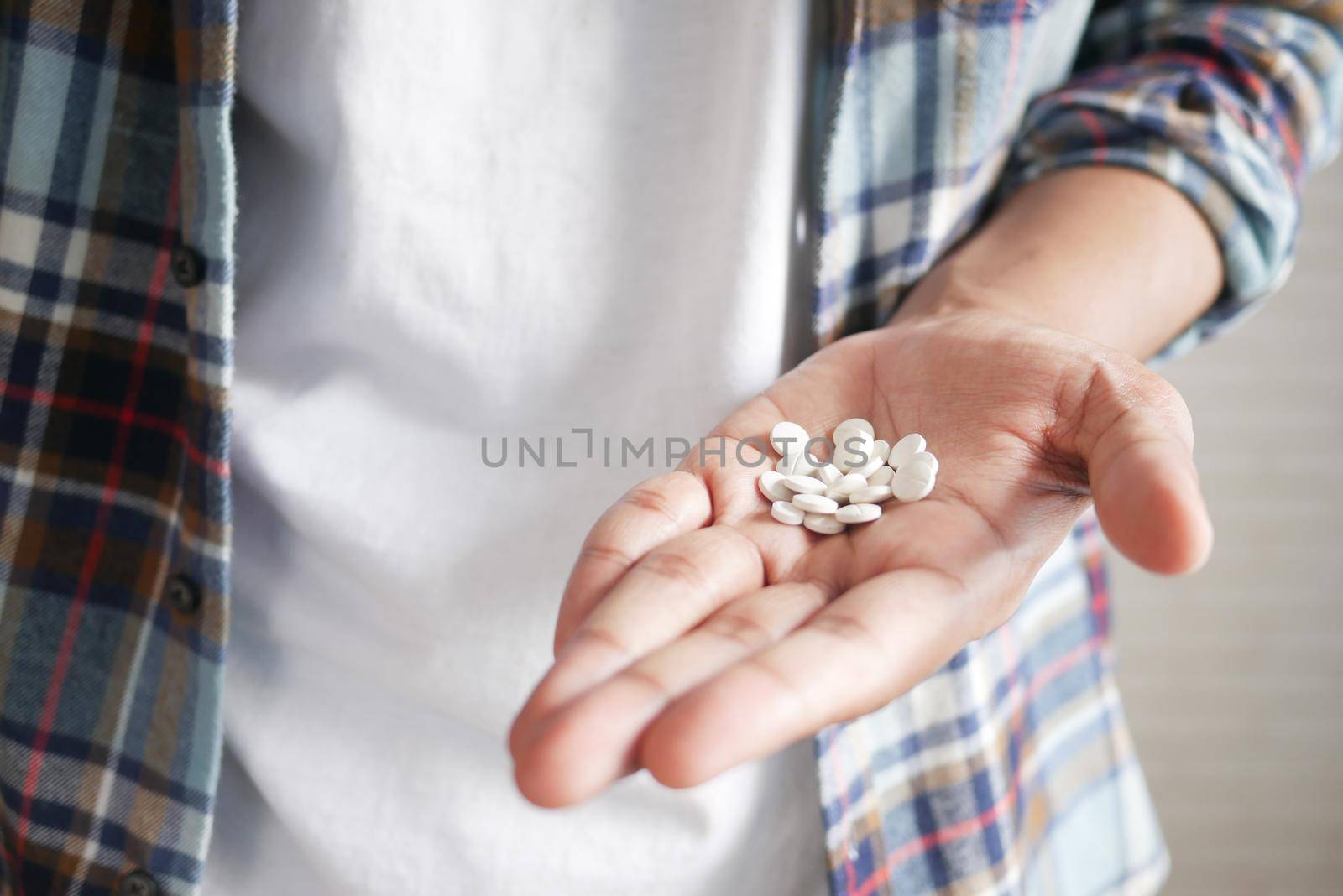 man's hand with pills spilled out of the container .