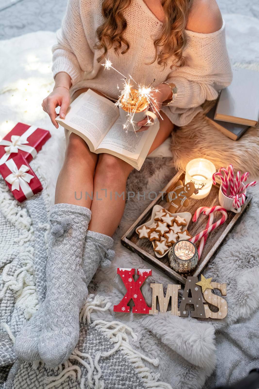 The girl is sitting in a christmas atmosphere, drinking a hot drink and reading a book by gitusik