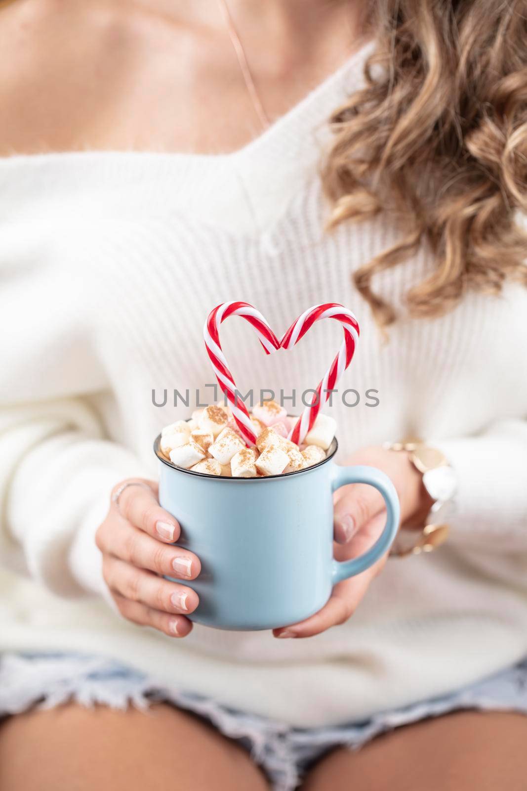 Girl in knitted wool sweater is holding a mug with hot chocolate with marshmallow. by gitusik