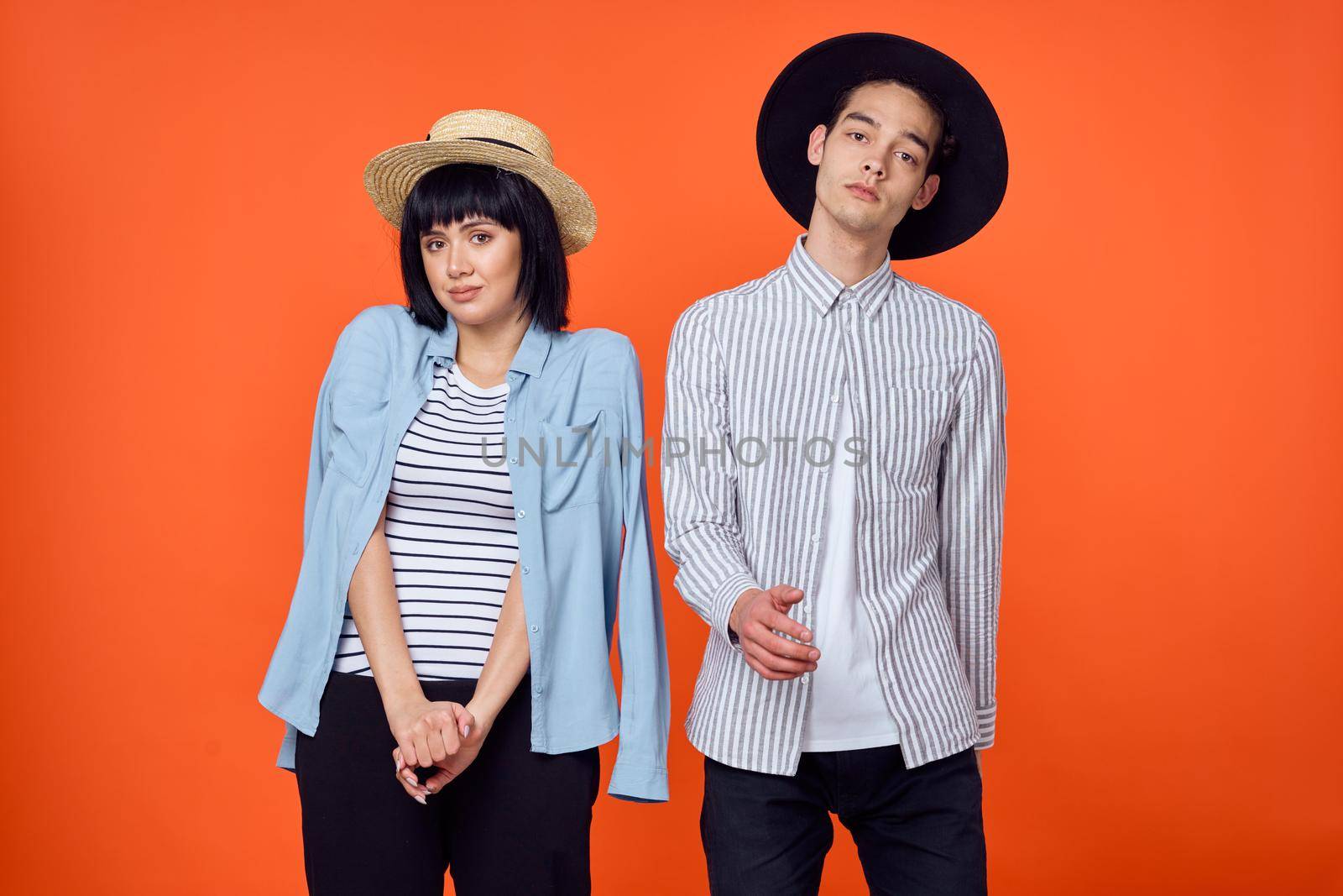 man and woman in hats posing fashion orange background by Vichizh