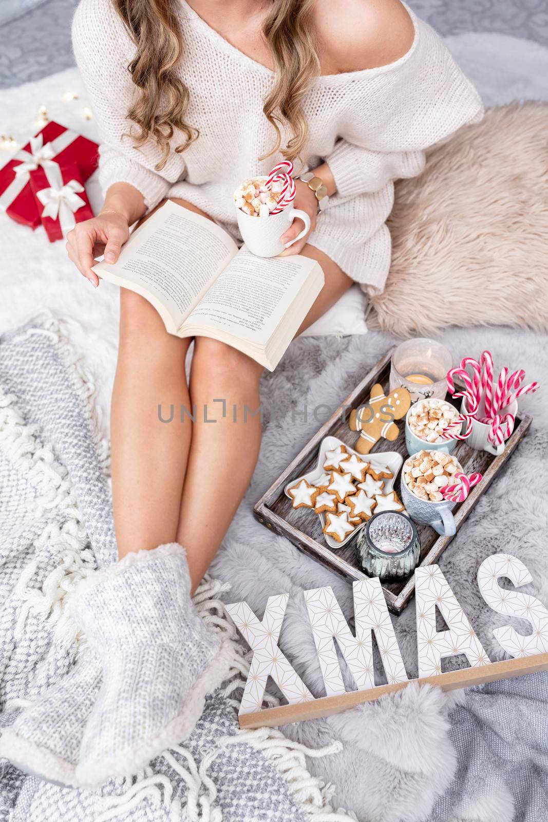 The girl is sitting in a christmas atmosphere, drinking a hot drink and reading a book by gitusik