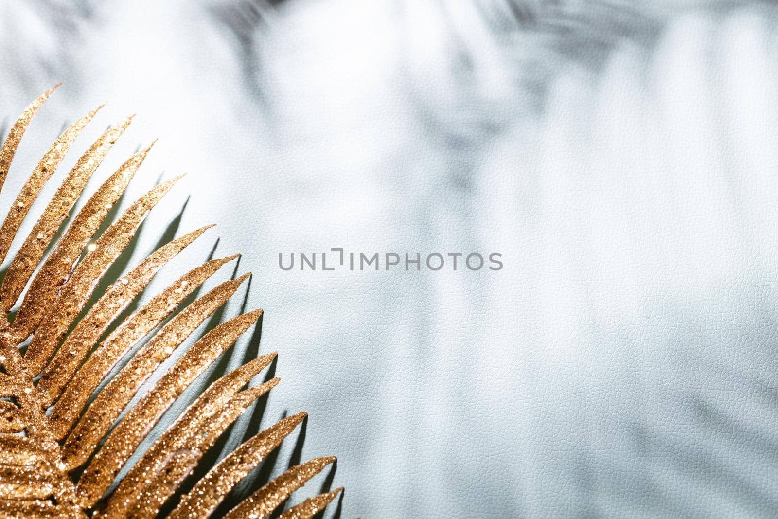 Gold palm leaves and shadows on a blue wall background.