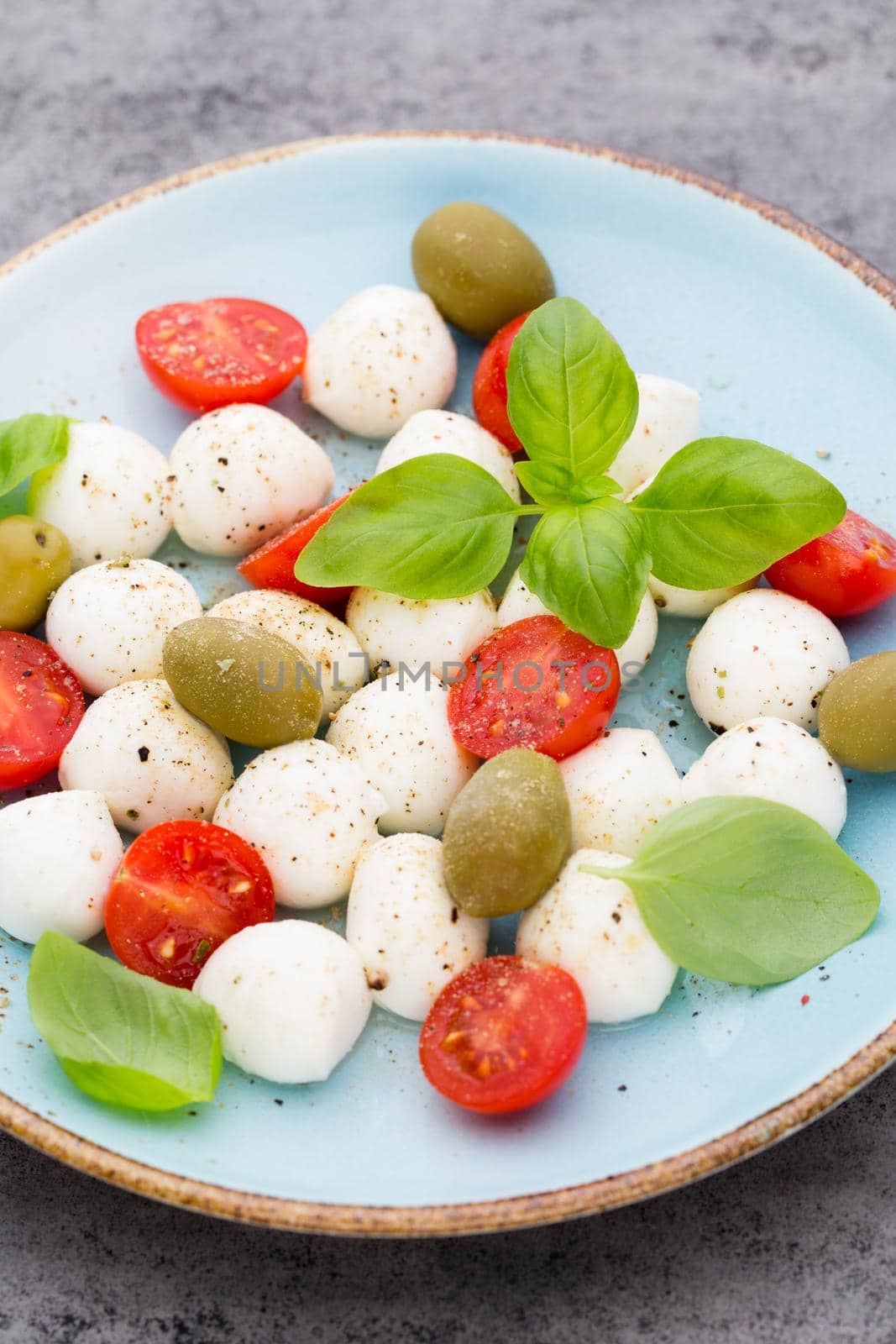 Delicious caprese salad with ripe cherry tomatoes and mini mozzarella cheese balls with fresh basil leaves. by gitusik