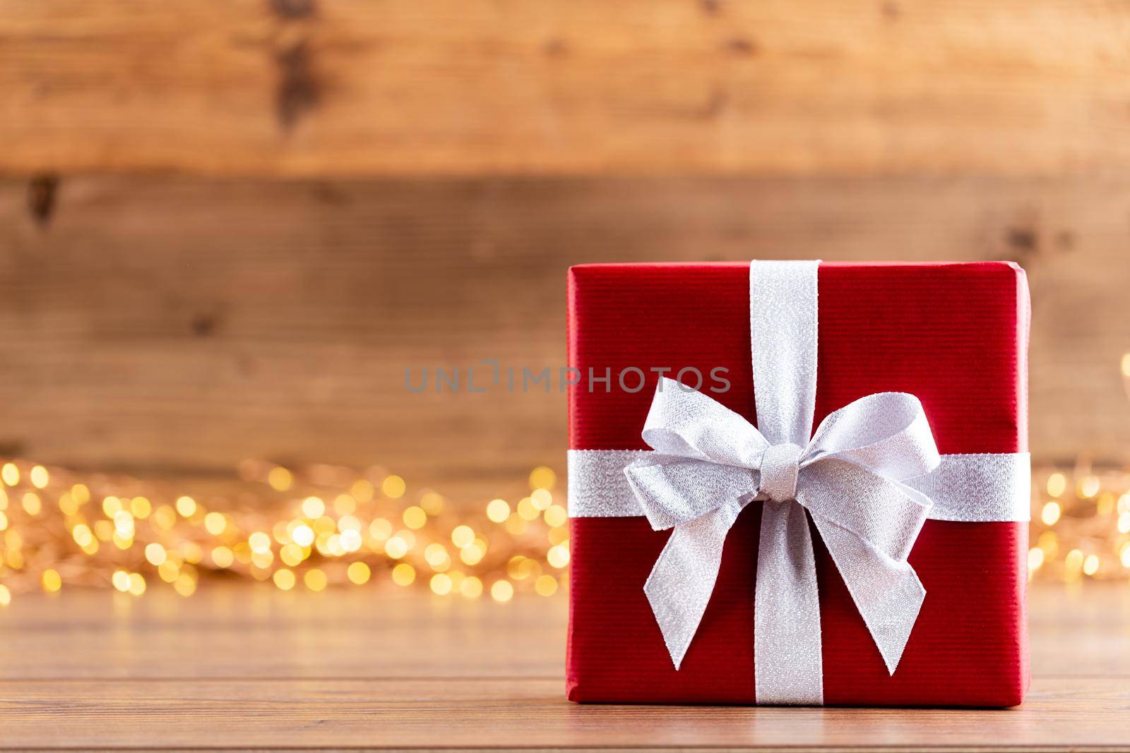 Christmas gift boxes with ribbons and tree on bokeh background.