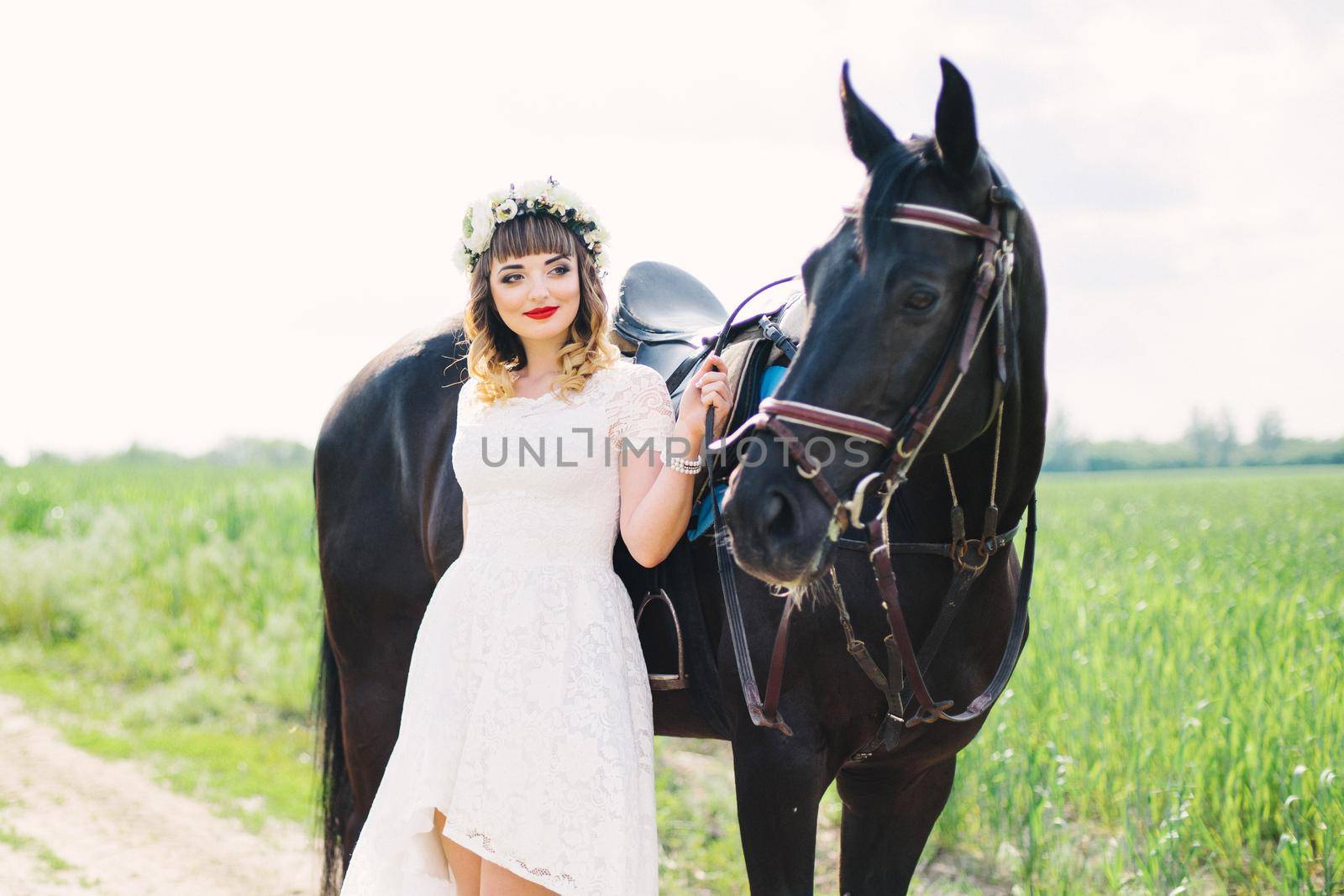 girl with red lips in a white dress near a black horse