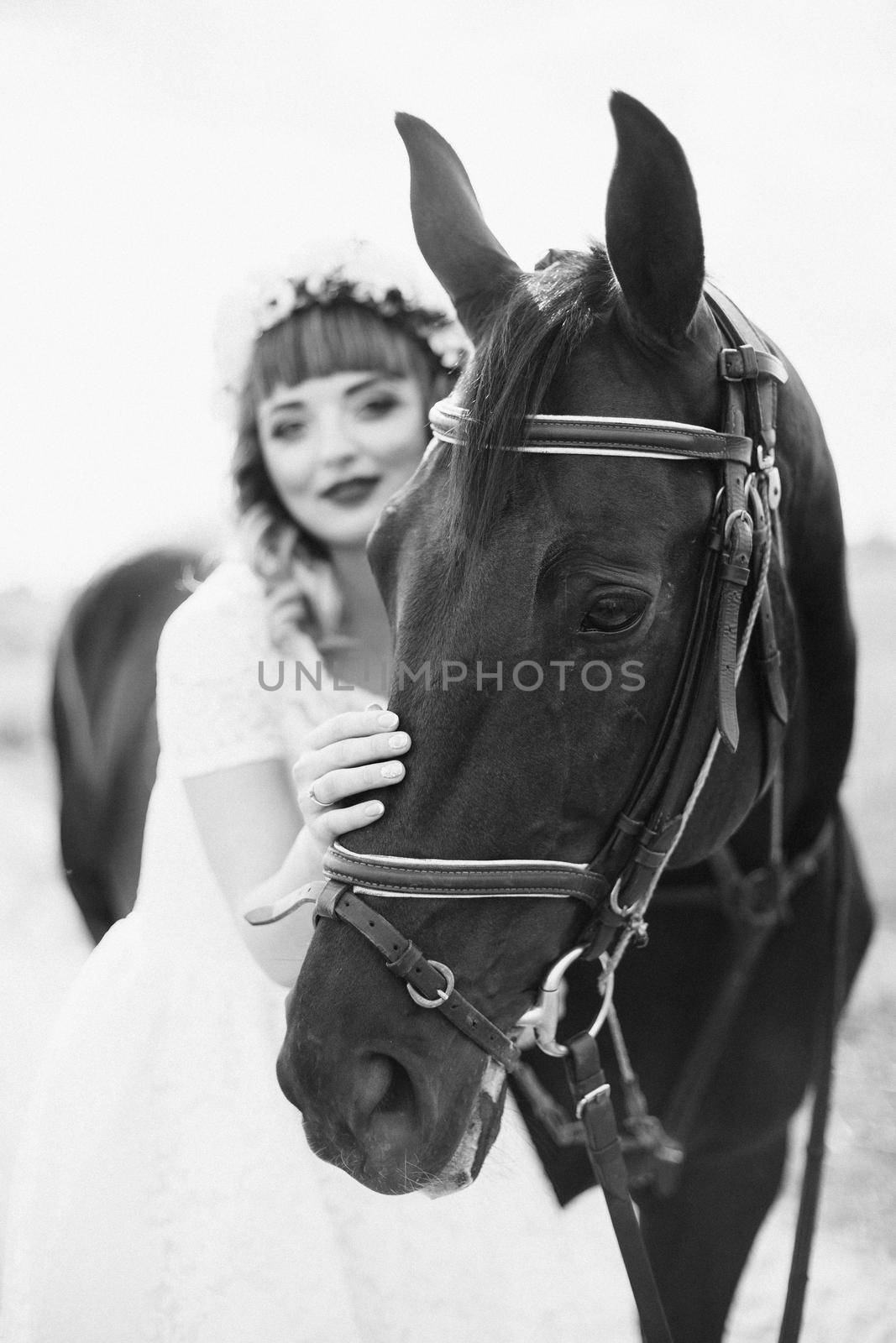 girl with red lips in a white dress near a black horse