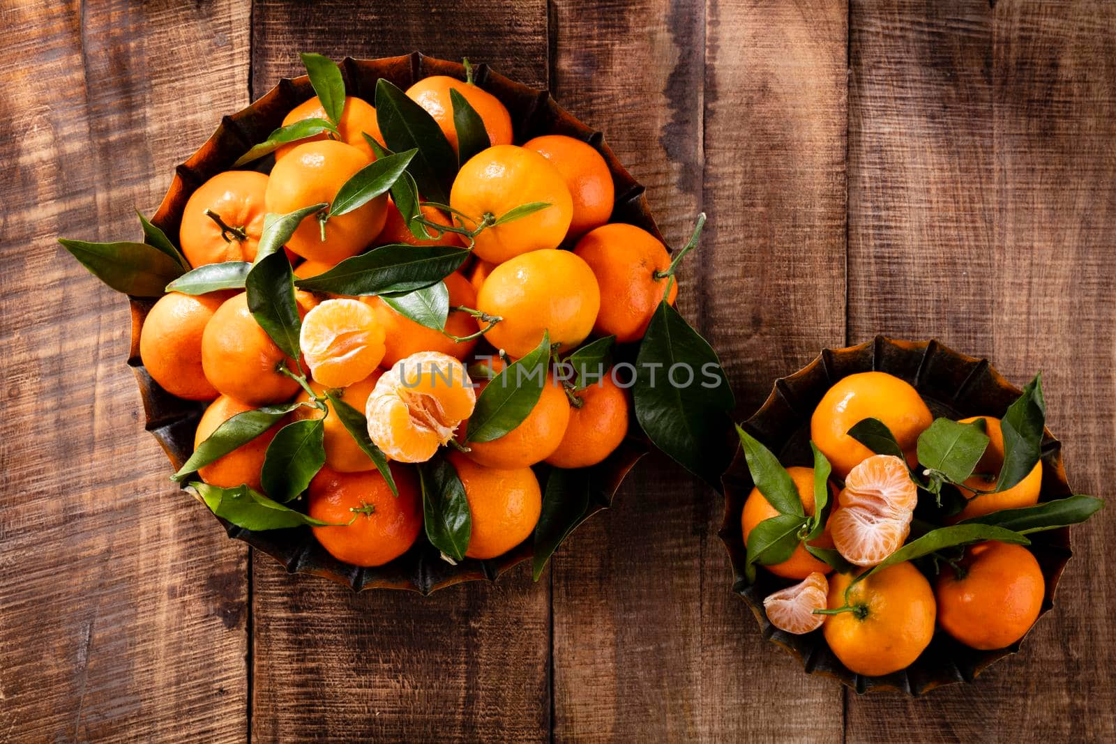 Fresh mandarin oranges fruit with leaves in wooden box, top view.