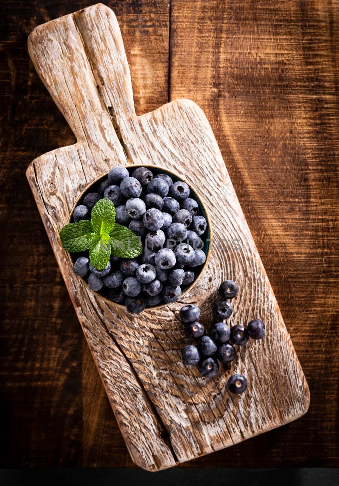 Bowl of fresh blueberries on rustic wooden board. Organic food blueberries and mint leaf for healthy lifestyle.