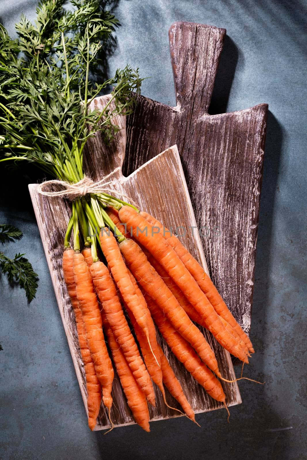 Organic carrot on wood cutting board, closeup photo.