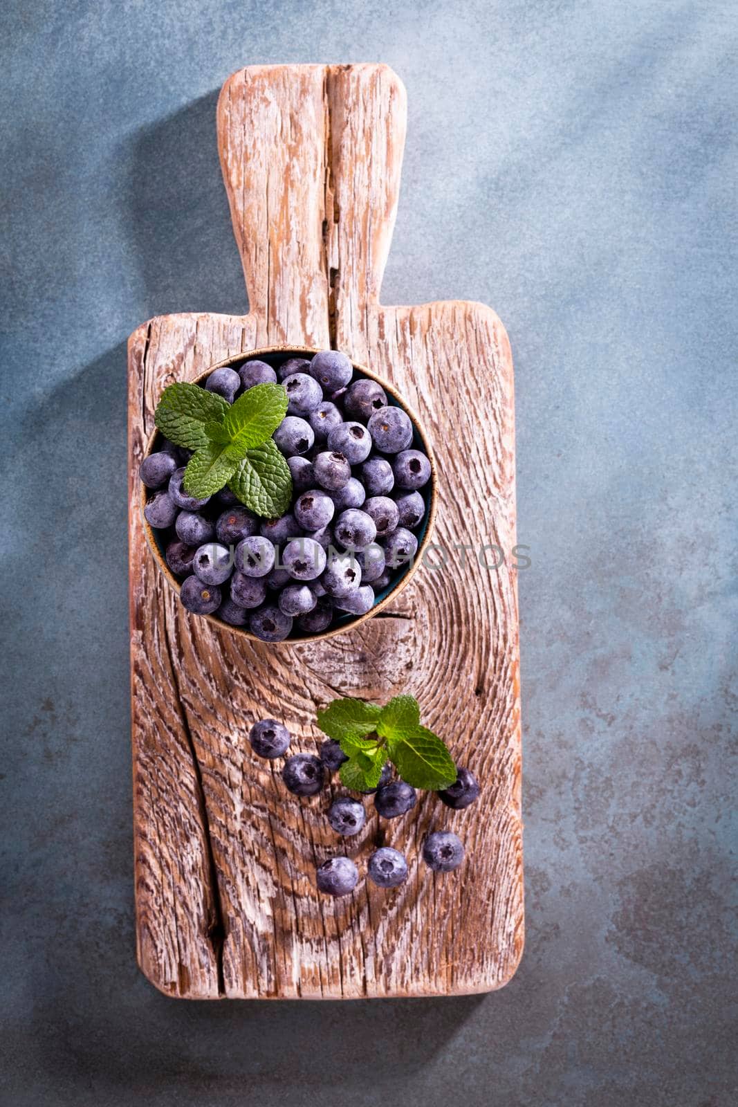 Bowl of fresh blueberries on rustic wooden board. Organic food blueberries and mint leaf for healthy lifestyle.