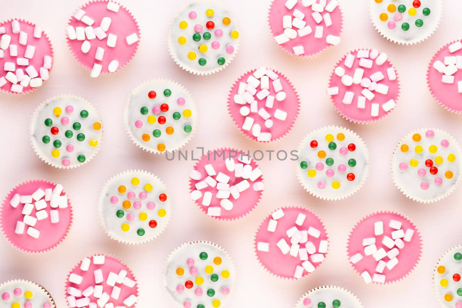Multiple colorful nicely decorated muffins on a white background, top view.
