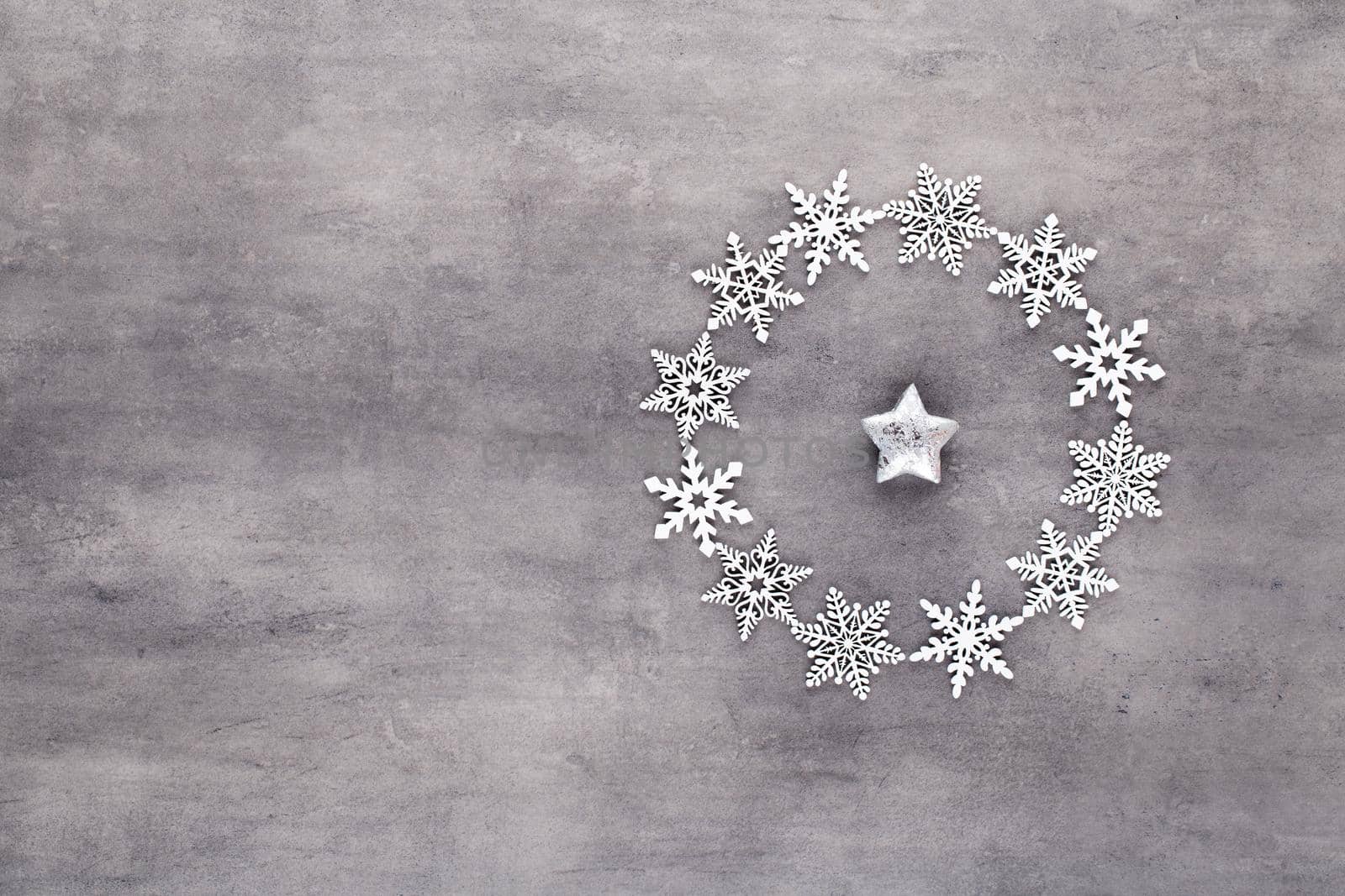 White snow flakes wreath decorations on gray background.  by gitusik