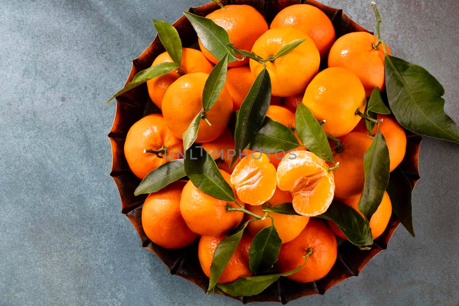 Fresh mandarin oranges fruit with leaves in wooden box, top view.