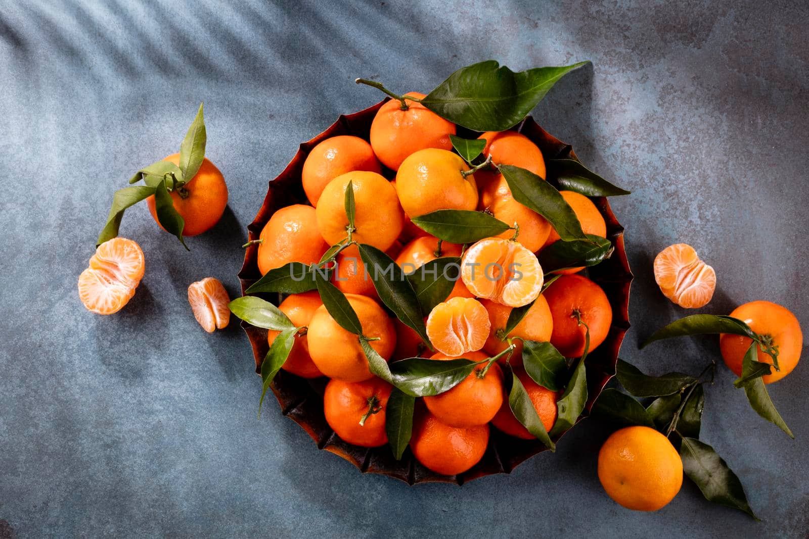 Fresh mandarin oranges fruit or tangerines with leaves in wooden box, top view by gitusik