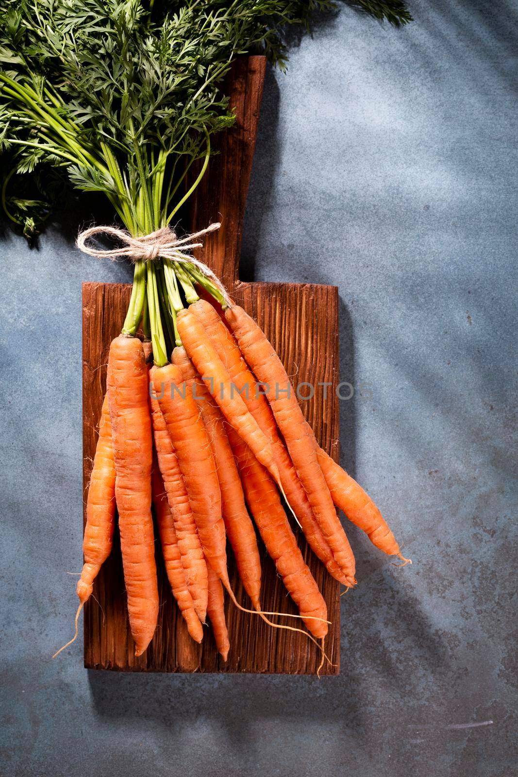 Organic carrot on wood cutting board, closeup photo. by gitusik