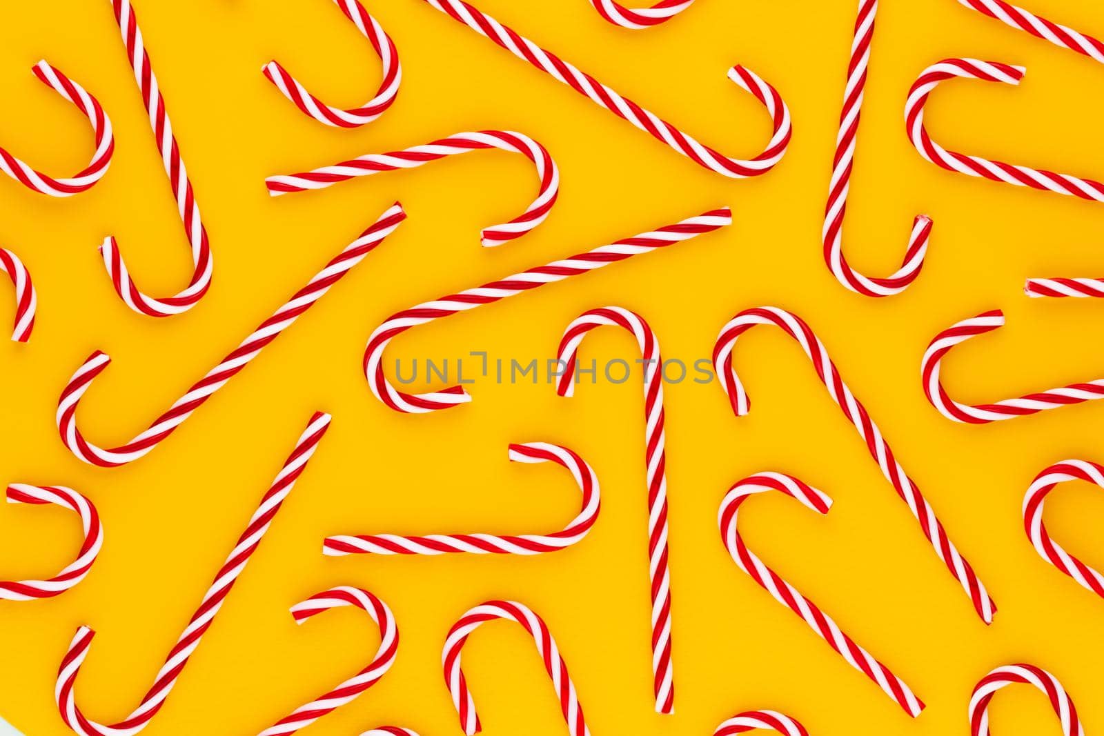 Christmas candy cane lied on yellow background. Flat lay and top view.