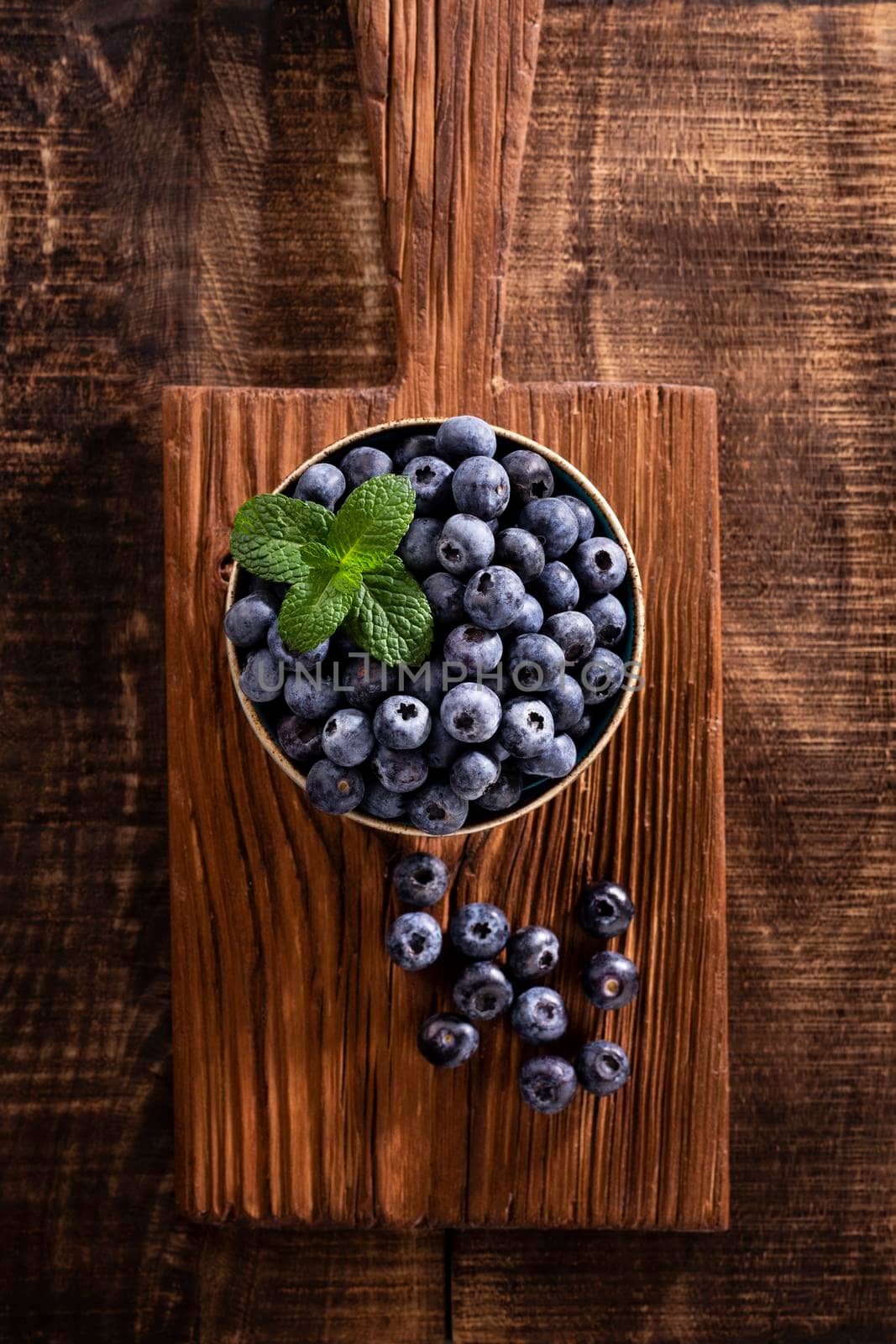 Bowl of fresh blueberries on rustic wooden board. Organic food blueberries and mint leaf for healthy lifestyle.