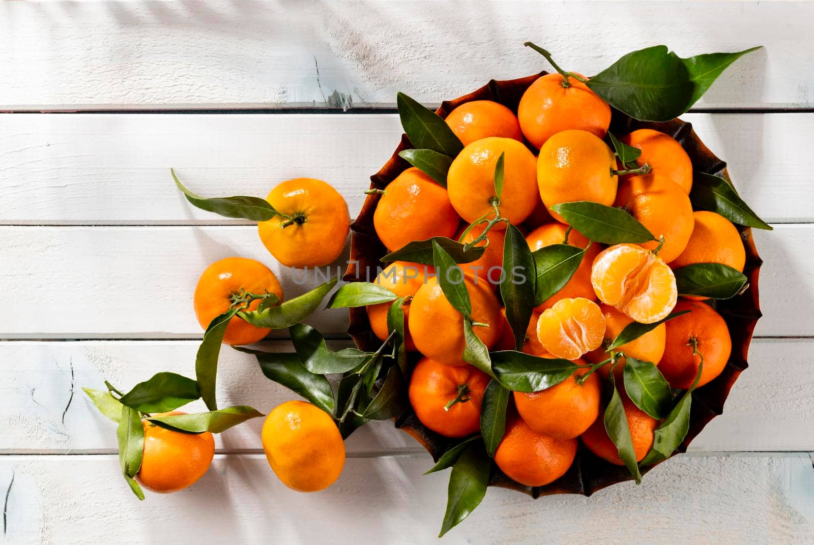 Fresh mandarin oranges fruit or tangerines with leaves in wooden box, top view by gitusik