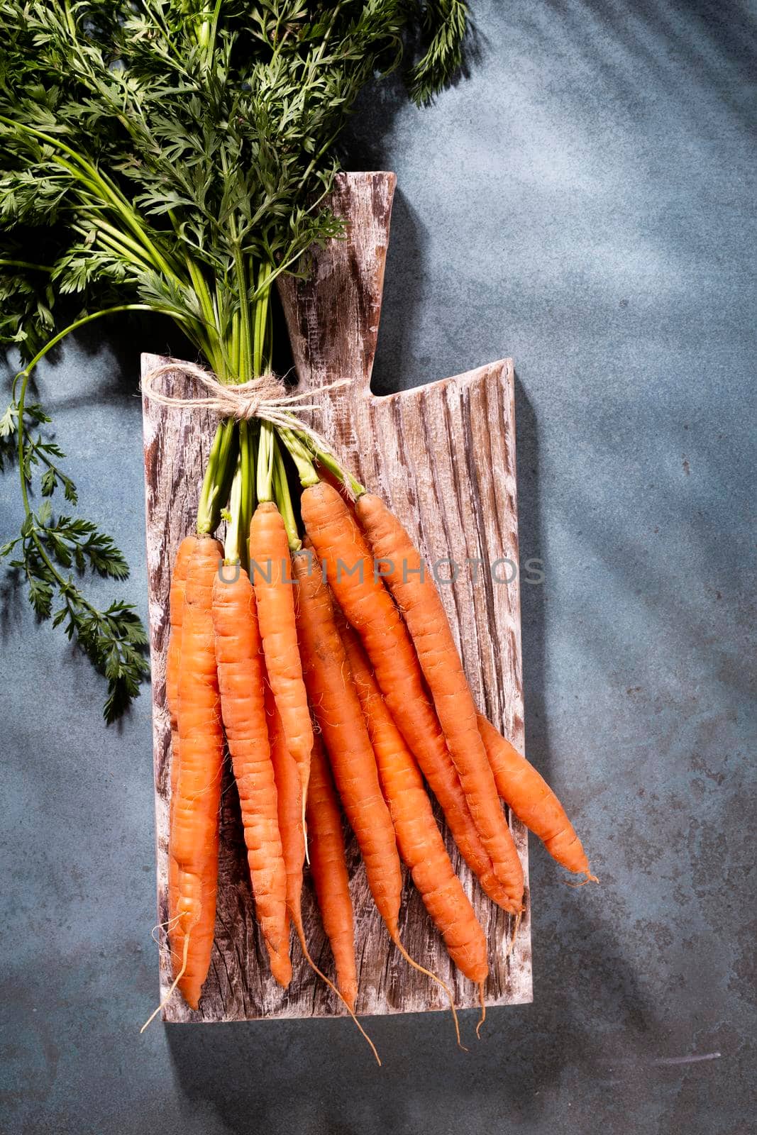 Organic carrot on wood cutting board, closeup photo.