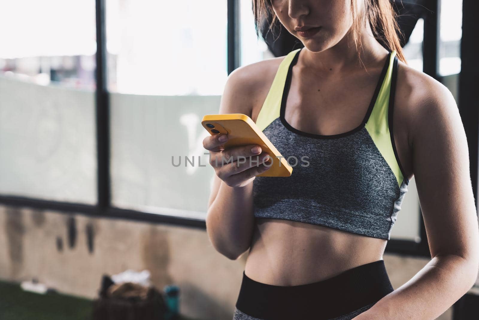 close up young fit woman using smart phone at gym.