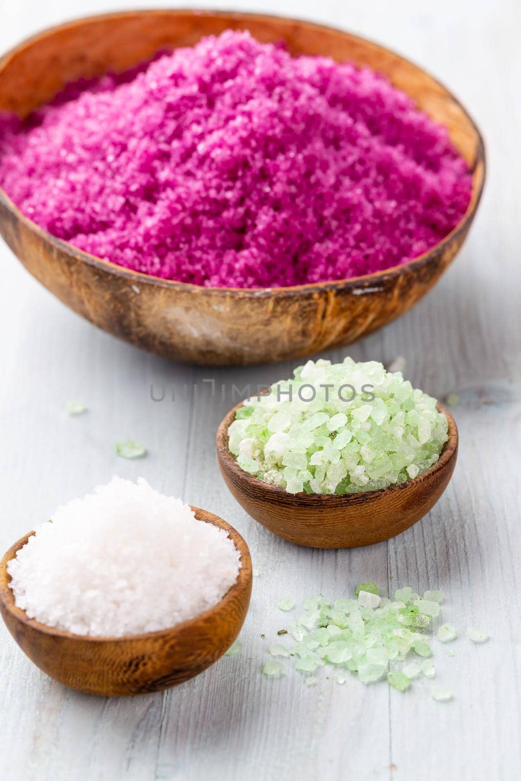 Sea salt in bowl, aroma oil in bottles, Wellness and flowers on grey textured background and flowers on vintage wooden background. Selective focus.  by gitusik
