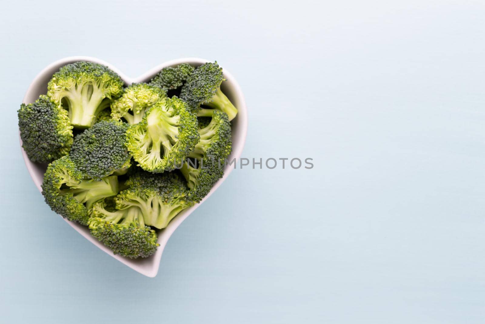 Fresh broccoli in a heart shaped bowl on a wooden background. by gitusik