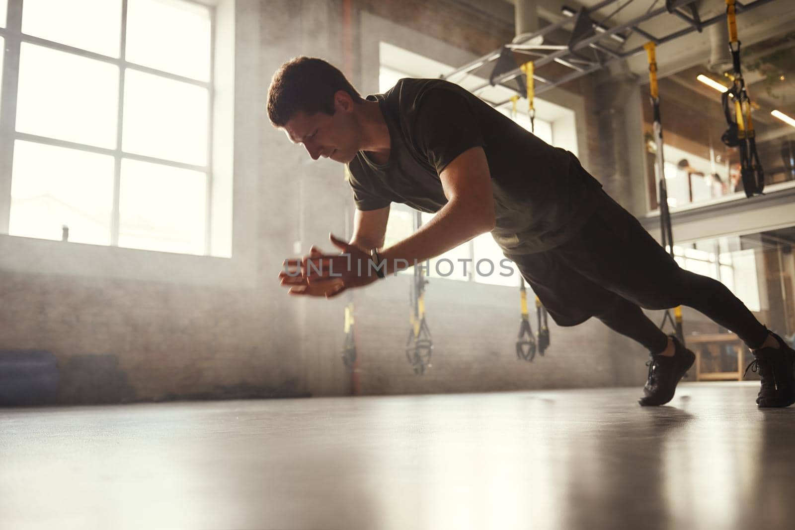 Strength and motivation. Full length of young athletic man in sportswear doing push-up exercises at gym. Sport concept. Bodybuilding. Fitness
