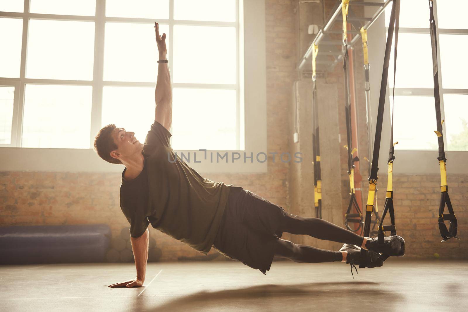 Making perfect body. Young athletic man exercising with suspension straps at gym. TRX Training. Fitness concept. Active life
