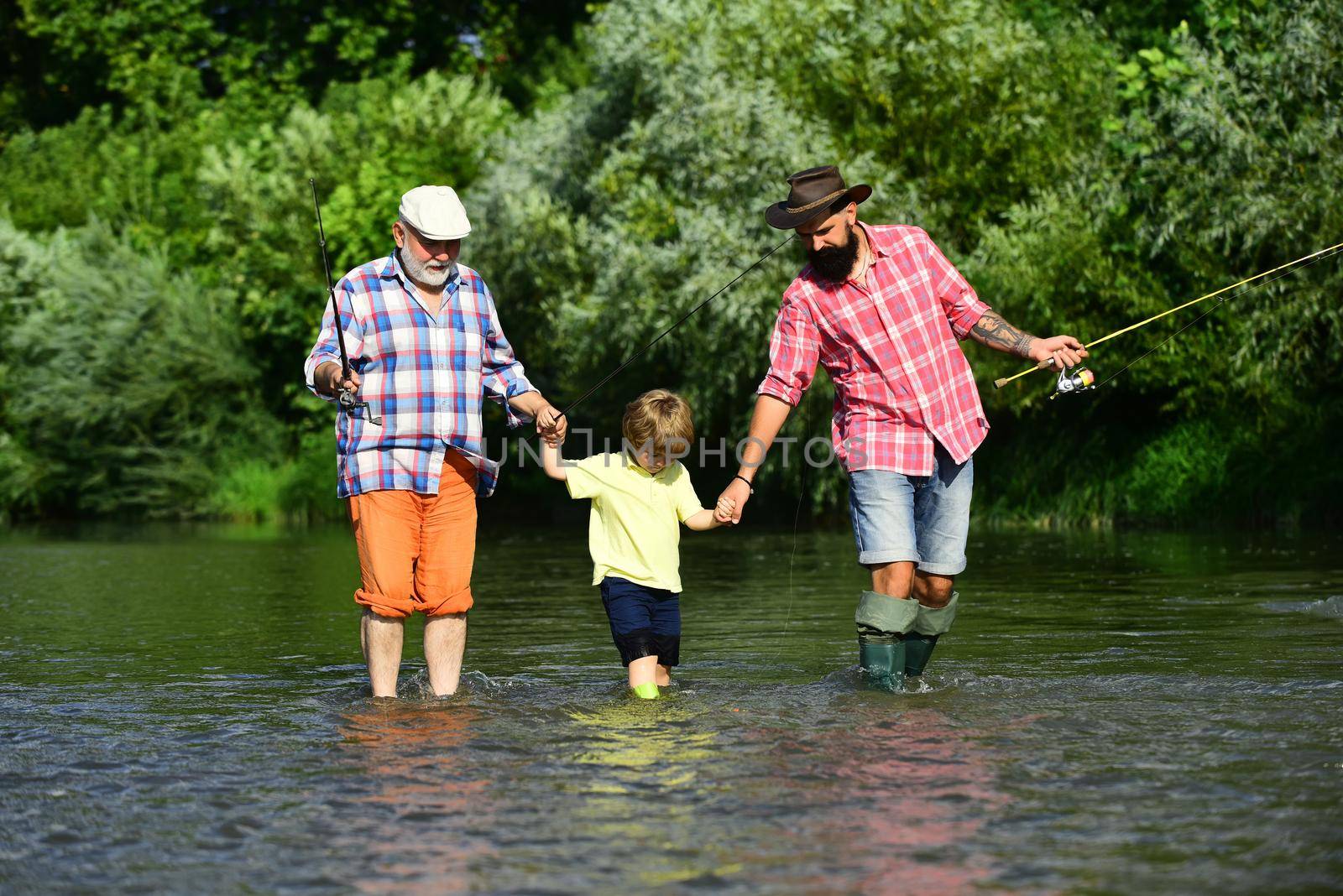 Three generations ages: grandfather, father and young teenager son. Father, son and grandfather relaxing together. Fly fisherman using fly fishing rod in river