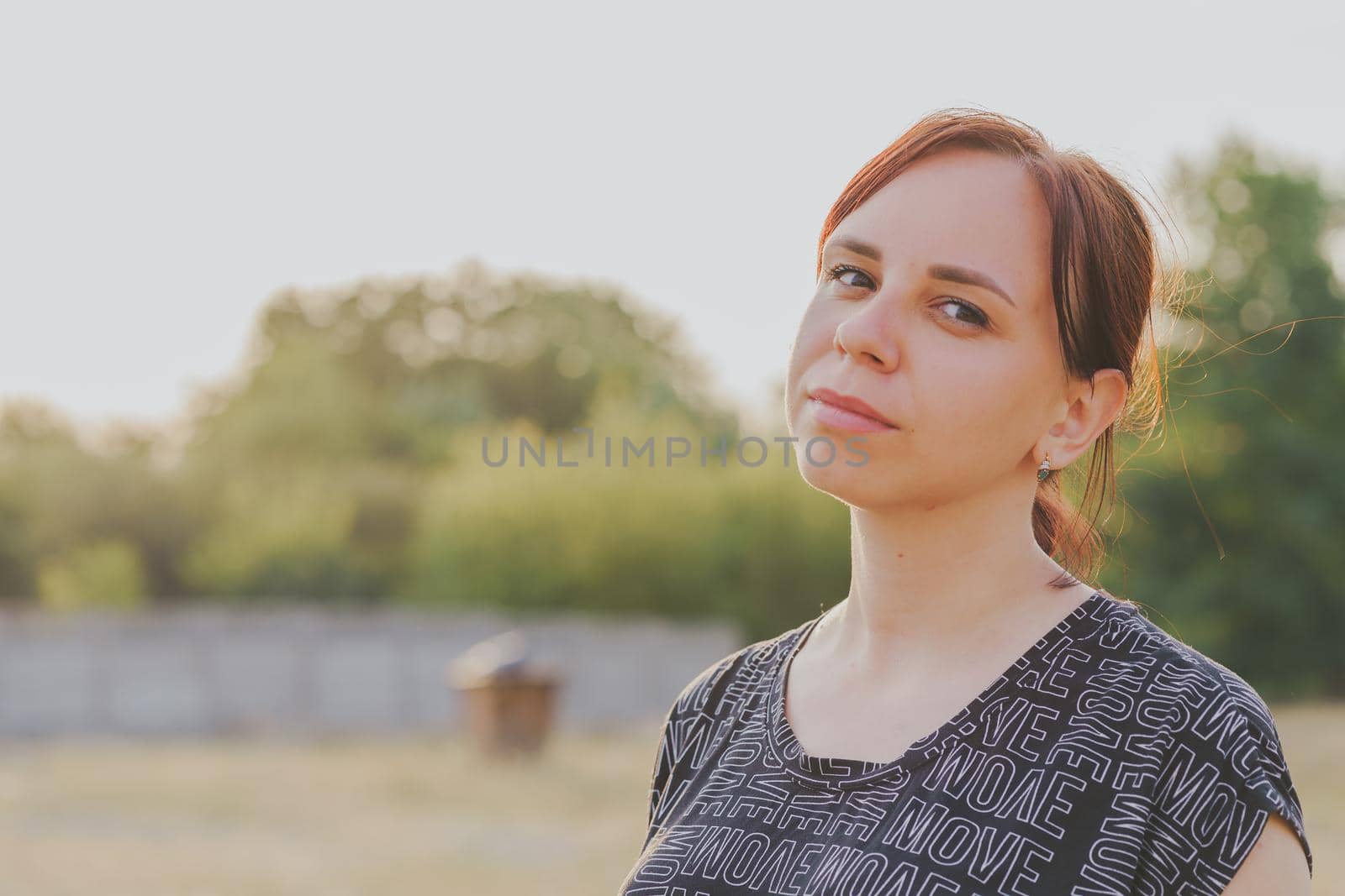 Portrait of young smiling woman on street during sunset. Close up of female looking at camera in countryside. by epidemiks