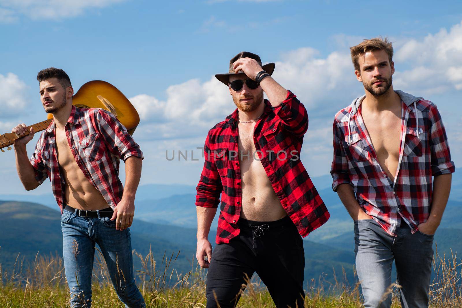 A group of people with guitar walking in the mountains. Hikers relaxing on top of a mountain and enjoying the view of valley. Couple of Young Happy Travelers Hiking on the Beautiful Rocky Trail