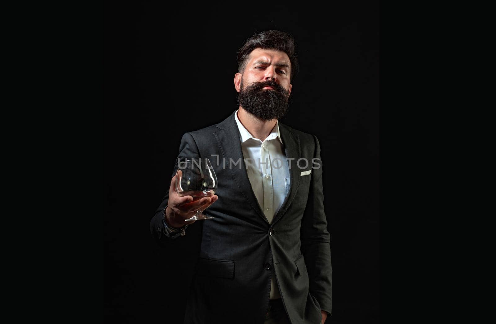 Businessman gets rid of stress with cognac. Bearded businessman in elegant suit with glass of cognac. Man Bartender holding glass of cognac