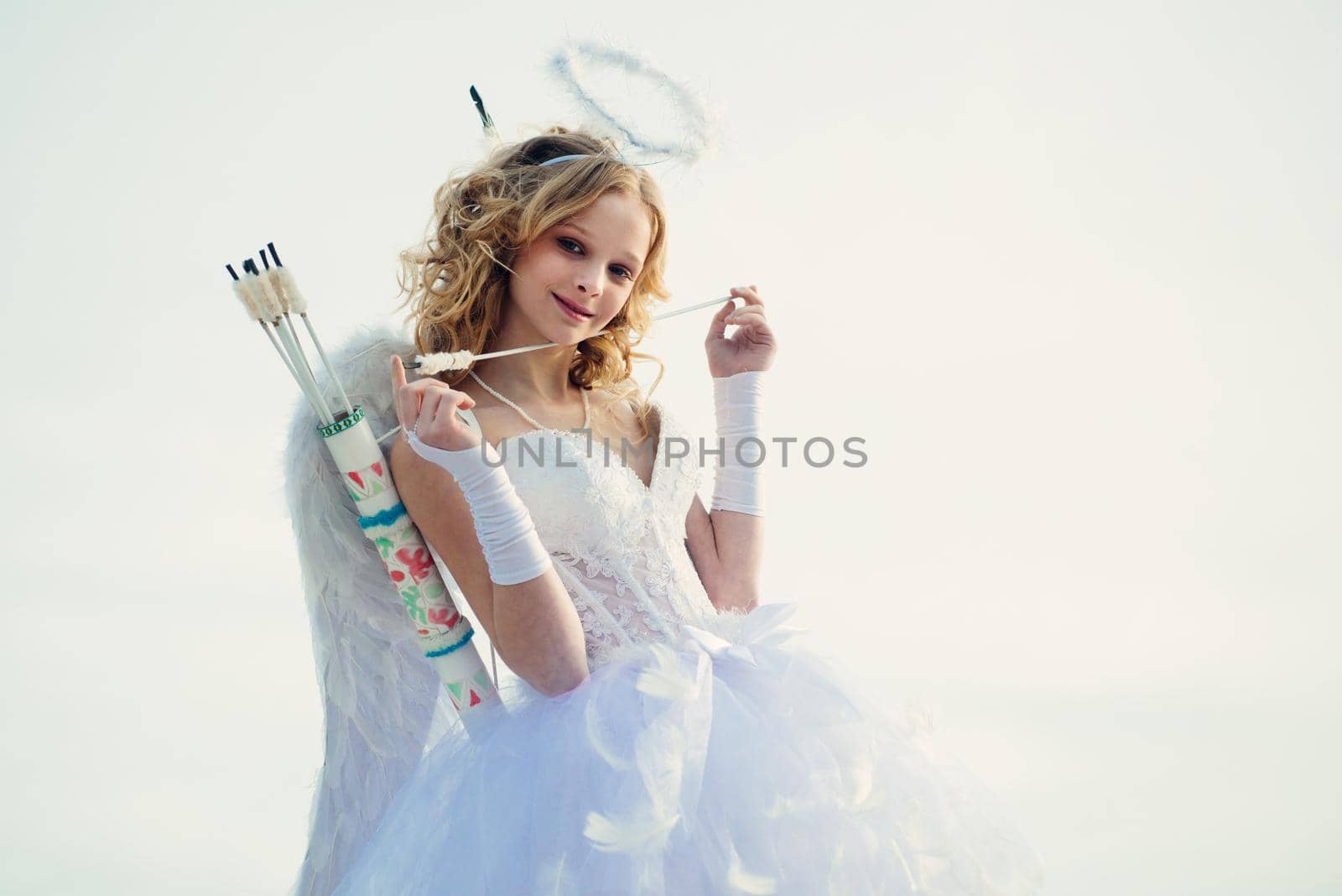 Arrow of love. Cupid in valentine day. Teen angel. Cupid cute angel with bow and arrows. Charming curly little girl in white dress and wings - angel cupid girl.