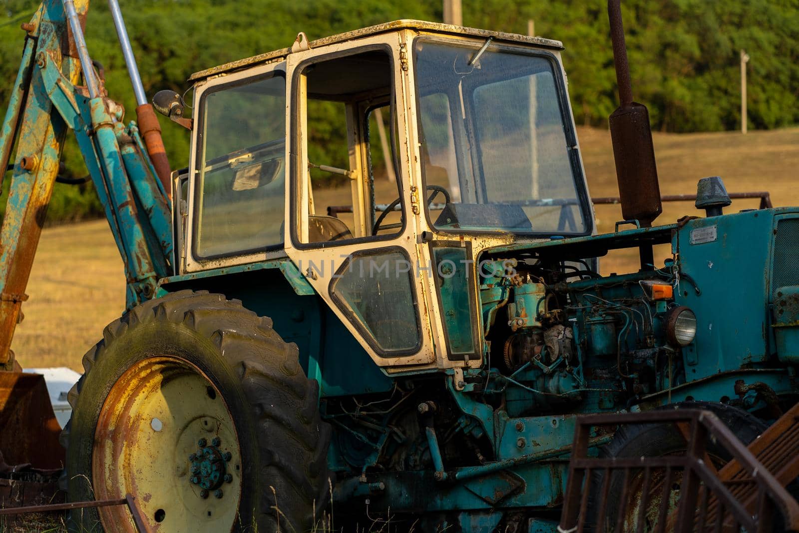 Weathered excavator digging ground during agricultural works in field on summer day in countryside