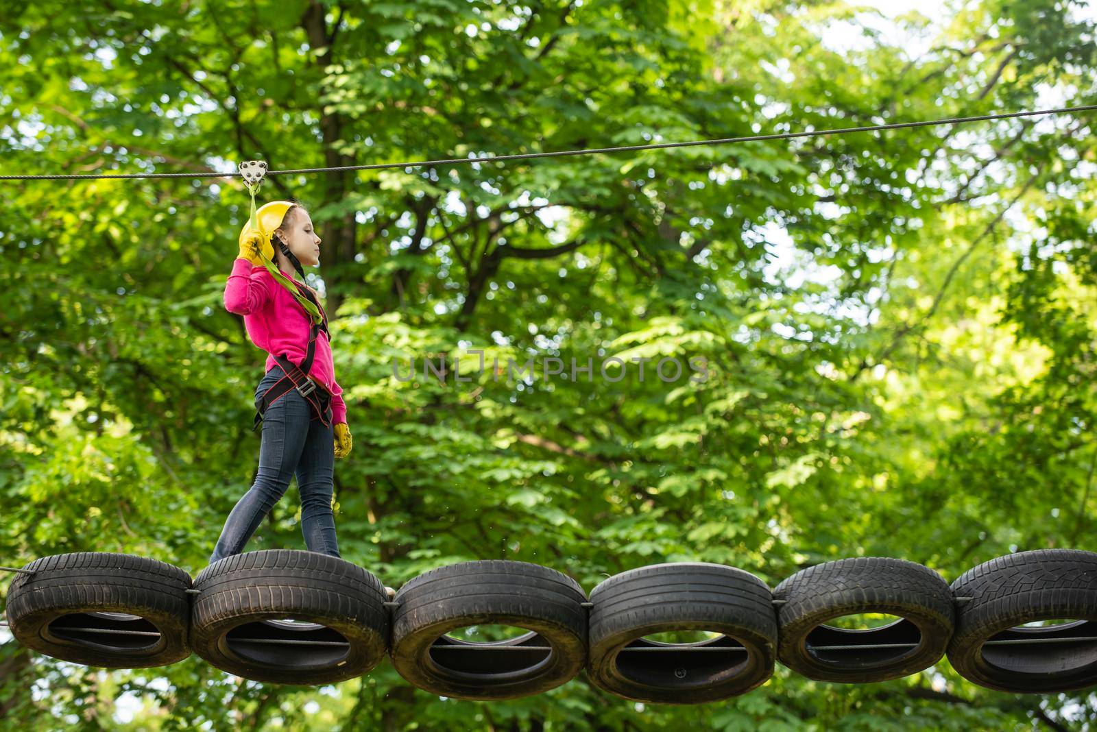 Active children. Helmet - safety equipment for Child playing. Cargo net climbing and hanging log. Eco Resort Activities. Safe Climbing extreme sport with helmet. High ropes walk