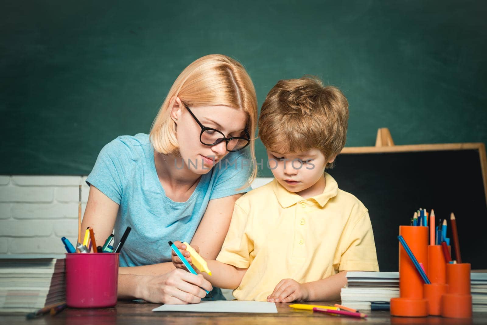 Back to school and happy time. Teacher and kid. Teacher helping kids with their homework in classroom at school. School and kid concept. by Tverdokhlib